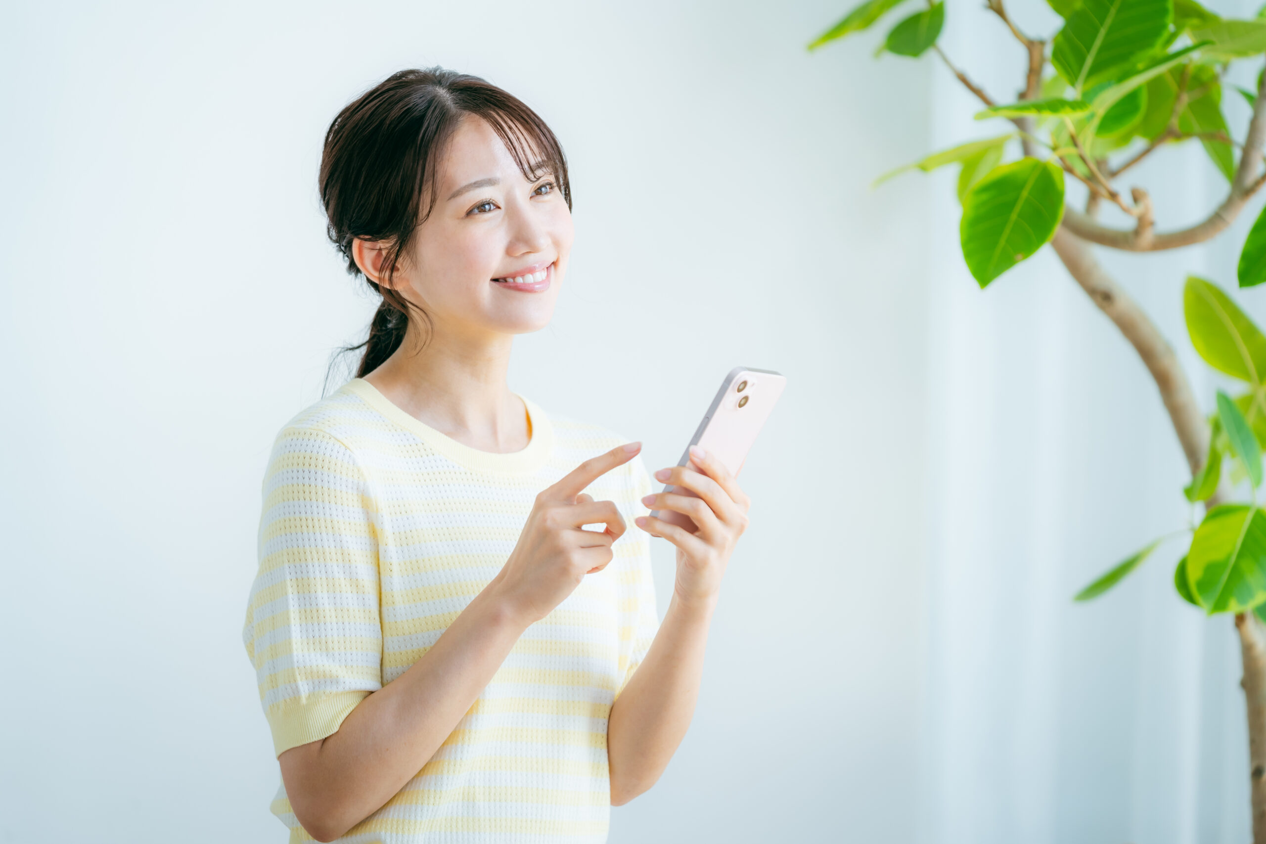 部屋でスマホを操作する女性
